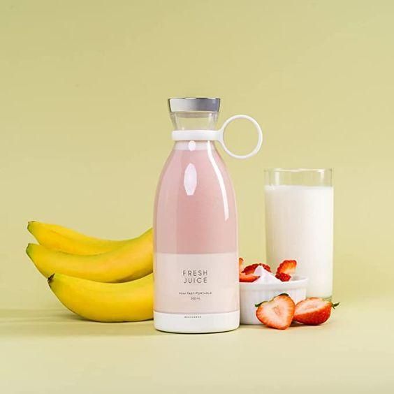 Portable juice blender preparing a fresh smoothie with strawberries and banana on a kitchen counter.